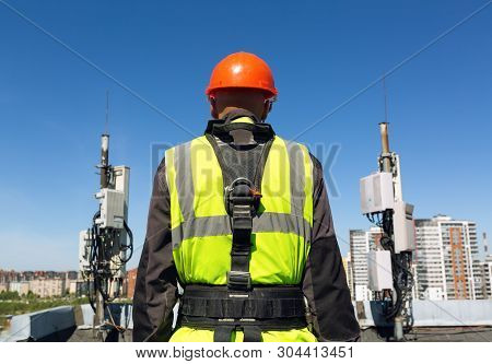 Professional Industrial Climber   In Helmet And Uniform Holds Telecomunication Equipment In His Hand