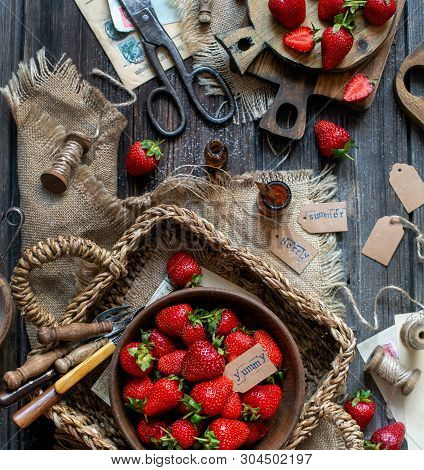 Overhead Shot Of Tasty Ripe Strawberries In Wooden Bowl Stands In Wicker Strawy Basket On Rustic Tab