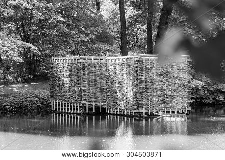 Wooden Building On The Shore Of The Pond. Wicker Building In The Forest.