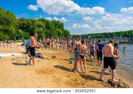 Many People Standing And Resting On Sand Close By The Water At The Rusalka Lake Beach With Pier On C