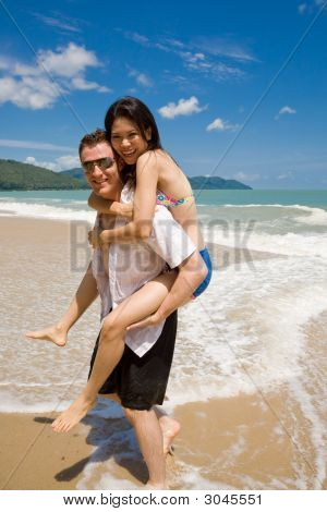 Hunk transporterar kvinna Piggyback stil Ath Beach