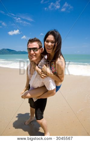 Hunk transporterar kvinna Piggyback stil Ath Beach