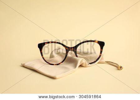 Modern Fashionable Acetate Spectacles, Torture Color With Textile Beige Bag Laying On Light Yellow B