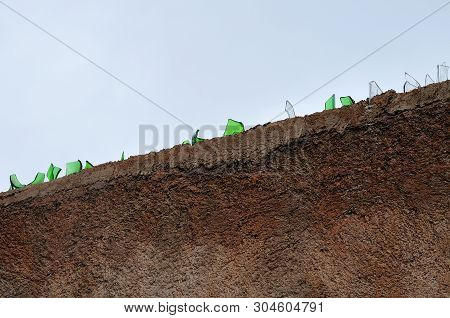 Broken Glass Pieces On Top Of A Garden Wall As Burglar Repellent