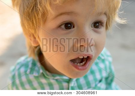 Scream. Shout Outcry. Young Blond Boy In A Green And White Shirt Screams With Open Mouth. Close-up P