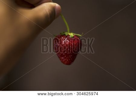 In The Twilight A Man Is Sexually Holding Strawberries In His Hand Close-up
