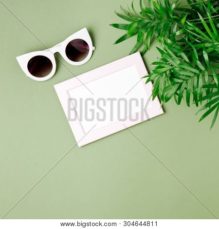 Tropical Leaves And Photoframe  On A Green Background With Space For Text. Top View, Flat Lay.
