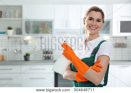Portrait Of Young Woman With Sprayer In Kitchen. Cleaning Service