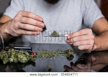 Man Preparing And Rolling Marijuana Cannabis Joint. Close Up Of Addict Lighting Up Marijuana Joint W