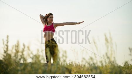Young Woman Doing Stretching Outdoor. Warm up Exercise in the Hot Summer Evening. Sport and Healthy Active Lifesyle Concepta.