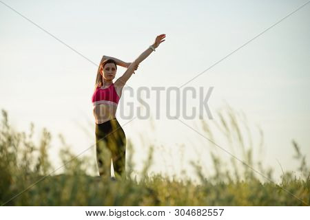 Young Woman Doing Stretching Outdoor. Warm up Exercise in the Hot Summer Evening. Sport and Healthy Active Lifesyle Concept.