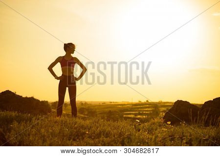 Young Woman Doing Stretching Outdoor. Warm up Exercise Against a Hot Beautiful Summer Sunset. Sport and Healthy Active Lifesyle Concept.