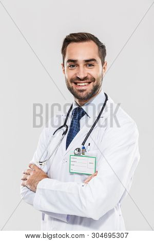 Portrait of caucasian young medical doctor with stethoscope smiling at camera and standing wth arms crossed isolated over white background