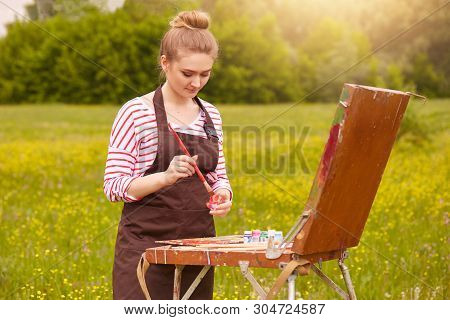 Portrait Of Beautiful Female Looking At Watercolour Samples On Convas, Mixed Colours, Has Concentrat
