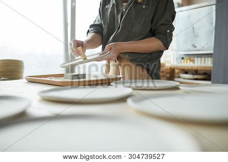 Mid Secion Portrait Of Unrecognizable Young Woman Sanding Handmade Ceramic Bowl In Pottery Workshop,