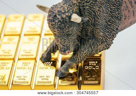 Bull Market In Gold Investment Concept, Closed Up Of Bull Figure On Gold Bar Or Ingot.