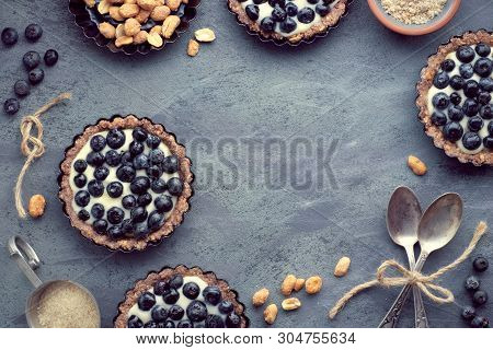 Top View On Wholegrain Blueberry Tarts With Vanilla Cream On Dark Background