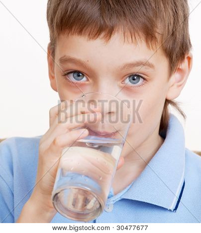 子供は水を飲む。少年はガラスから水を飲む