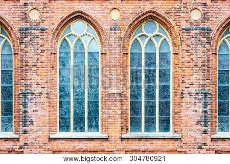Tall Windows With Pointed Arches On The Background Of The Old Wall Of Red Brick. From The Window Ser