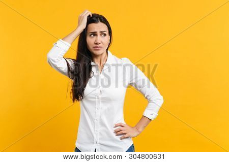Portrait Of Preoccupied Pensive Young Woman In White Shirt Looking Aside, Putting Hand On Head Isola