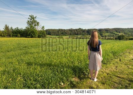 Young Woman With Long Hairs Enjoying The Beauty And Fragrance Of Spring Fields.