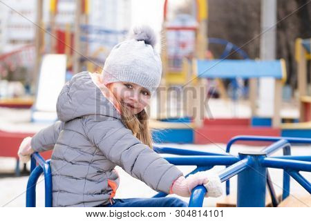 Happy child playing on rotating wheel toy at local playground at leisure time