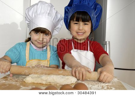 Due bambine cucinare una pizza in una cucina.Ragazzino in una cucina insieme.
