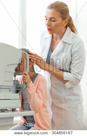 Gentle Serious Ophthalmologist Correcting Position Of Her Young Patient