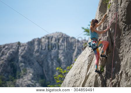Rock Climbing And Mountaineering In The Paklenica National Park. A Woman Overcomes A Challenging Cli