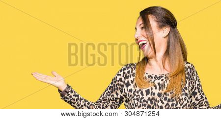 Beautiful middle age woman wearing leopard animal print dress Smiling showing both hands open palms, presenting and advertising comparison and balance
