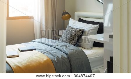 Pillows And Cushions In White And Black Color Tone On Single Bed And Bedside Table With Picture Fram