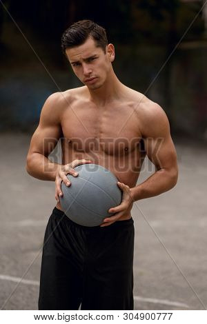 Frontal Portrait Of A Fit, Strong Shirtless Young Man On A Bascketball Court, Isolated On A Street B