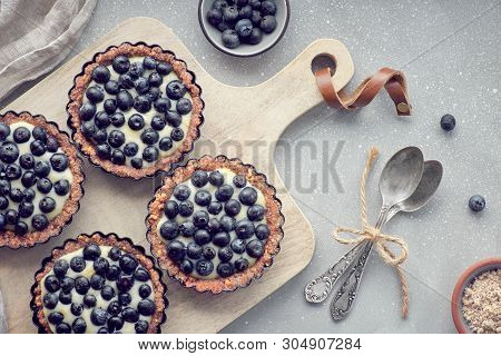 Top View On Wholegrain Blueberry Tarts With Vanilla Cream On Light Textured Background