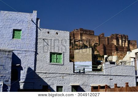 View Of Mehrangarh (mehran Fort) From Old Blue City. Brick Wall Of Old House On A Foreground. Jodhpu
