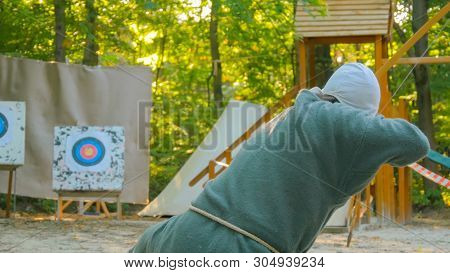 Medieval Male Archer Shooting Targets With Wooden Bow At Historical Festival. Archery And Medieval C