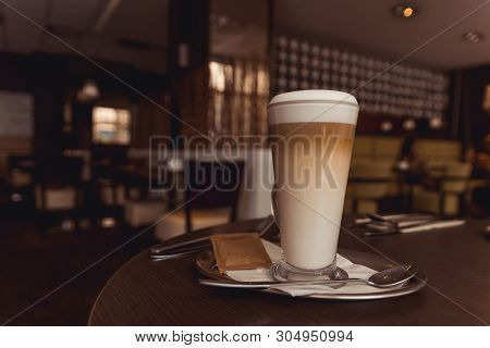 Cup Of Caffe Latte With Set Of Cutlery On Brown Table In Coffeehouse