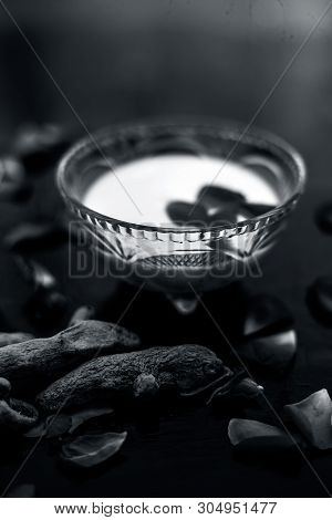 Milk Face Pack On Black Shiny Surface Consisting Of Raw Milk,turmeric Or Haldi And Badam In A Glass