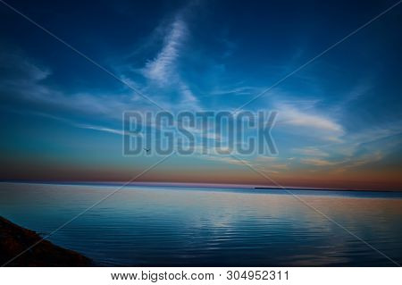 Beautiful Sunset Over The Water With Clouds On The Sky And A Seagull Above The Water.