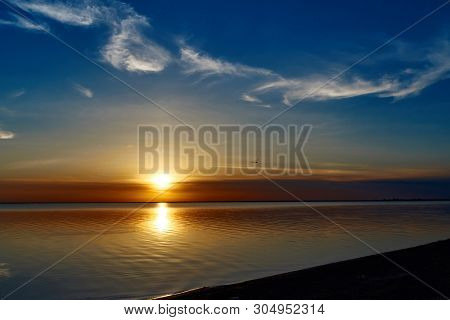 Beautiful Sunset Over The Water With Clouds On The Sky And A Seagull Above The Water.