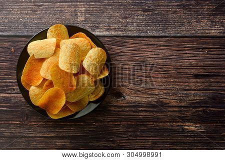 Potato Chips Over Wooden Background. Salty Crispy Snack. Isolated Chips.