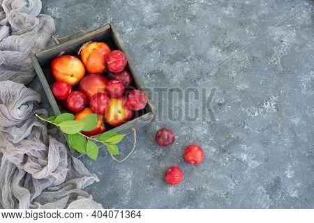 Ripe Golden And Red Plums And Peaches In Wooden Box On Concrete Background. Flat Lay, Top View , Spa