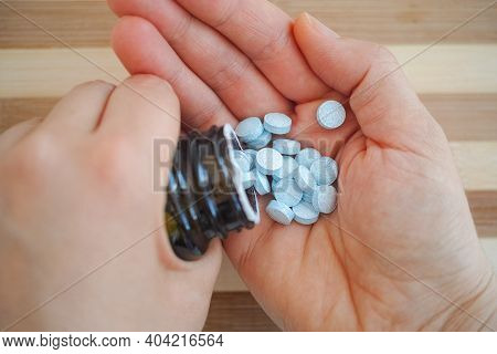 Woman Taking Chelated Copper Tablets Out Of A Bottle. Close Up.