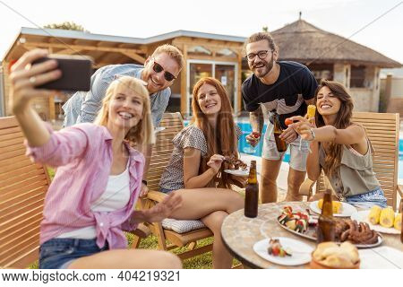 Group Of Friends Having A Backyard Poolside Barbecue Party, Having Fun Taking Selfies While Gathered