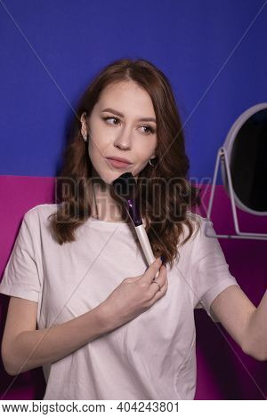 Charming Brunette Woman In White T-shirt With Makeup Brushes Isolated On Colorful Blue And Pink Back