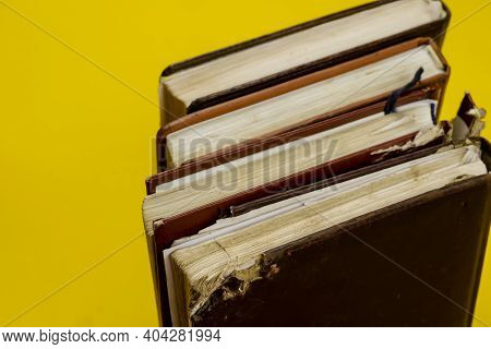 Four Old Diaries Standing On Endpaper On Yellow Background. The Diaries Have Worn Pages. View From A