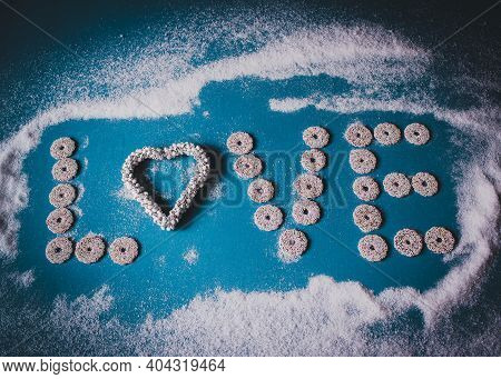 Holiday Concept For Valentine's Day. The Word Love On A Blue Surface With Snow. Letters From Round S