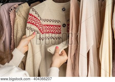 Woman Shopper, Customer Choosing Winter Pulover With Chtistmas Ornament From Assortment Of Clothing 
