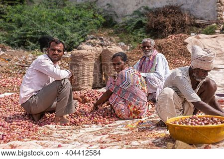 Lakundi, Karnataka, India - November 6, 2013: Closeup Of Group Of Farm Hands, One Woman, Squat Sorti