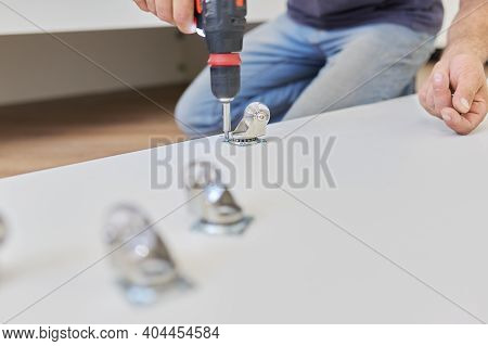 Furniture Assembly Parts, Furniture Wheels Close-up. Worker Hands Assembling Furniture Using Profess