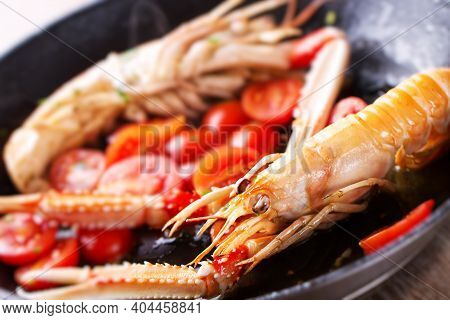 Scampi, Preparation And Cooking In A Pan. Shellfish Scampi Cooked In A Pan With Cherry Tomatoes